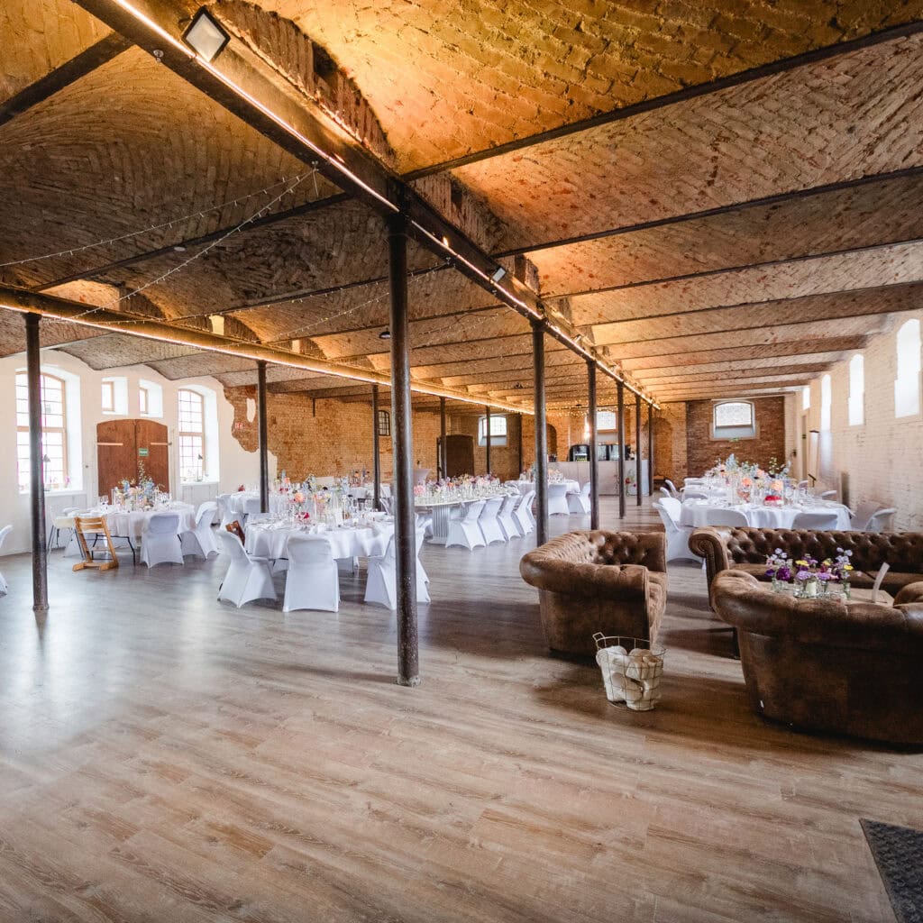 Hochzeitssaal in München mit rustikalem Charme, Bernstein-Decke und elegant gedeckten Tischen für die perfekte Hochzeitsfeier. Ideal für Hochzeitslocation in München mit stilvollem Ambiente und tollem Flair.